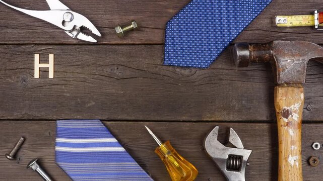 Happy Fathers Day wood letter greeting with tools and ties on a dark wood background. Stop motion video.