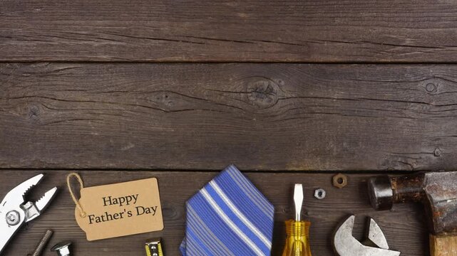 Happy Fathers Day gift tag with bottom border of tools and ties on a dark wood background. Stop motion loopable video.