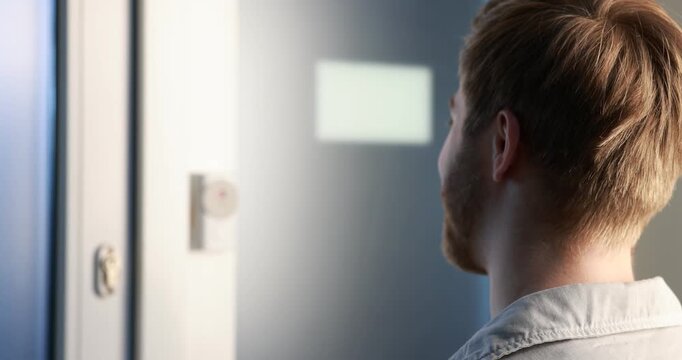 Man pressing button on intercom panel indoors, closeup