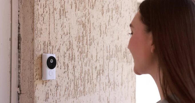Woman pressing button on intercom panel outdoors, closeup