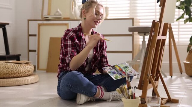 Woman painting with brush in studio, camera moving in. Slow motion effect