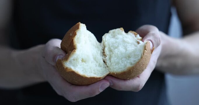 Man breaking fresh bread indoors, closeup view