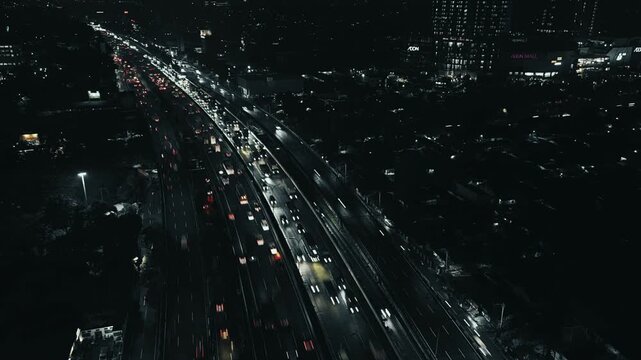 Aerial high angle view of heavy nighttime traffic congestion on a multi-lane city highway illuminated by glowing vehicle headlights.