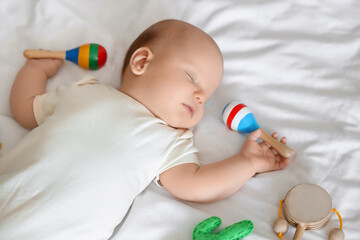Obraz premium Cute baby with toys sleeping on bed, top view