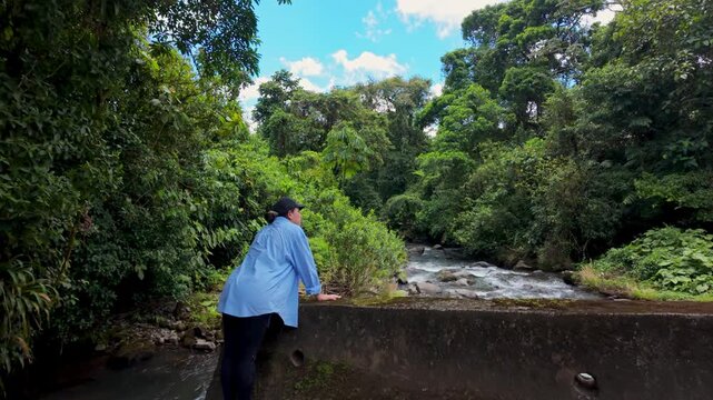 Woman admiring a flowing river in a lush green jungle