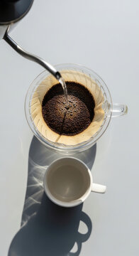 Coffee brewing process viewed from above with a glass server and a white mug