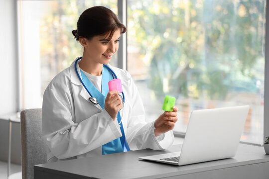 Female doctor with pill boxes video chatting in office