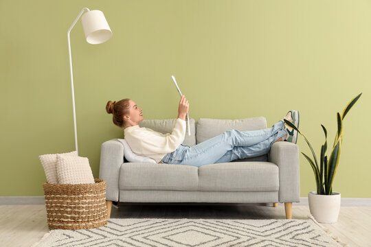 Young woman reading newspaper on sofa at home
