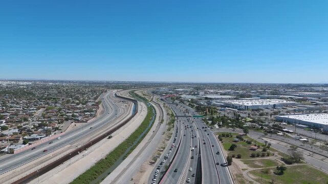 
Aerial shot showing the international border line between Ciudad Juarez, Chihuahua and El Paso, Texas featuring the border fence, Rio Grande, and heavy vehicle traffic on the main highways.