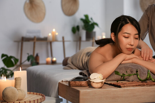Pretty young Asian woman having massage in spa salon