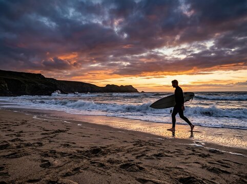 Surfer walking along a sandy beach with a surfboard at sunset, preparing for a late evening surf session in the ocean, representing an active coastal lifestyle