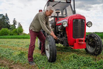 Obraz premium Man trying to repair a tractor on the field, using wrench, struggling 