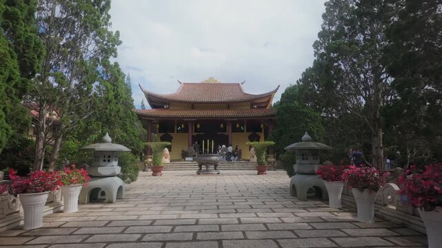 A serene view of the Thien Vien Truc Lam Pagoda in Da Lat, Vietnam, with visitors admiring its intricate architecture and lush gardens. The pagoda is a popular spiritual and tourist destination.