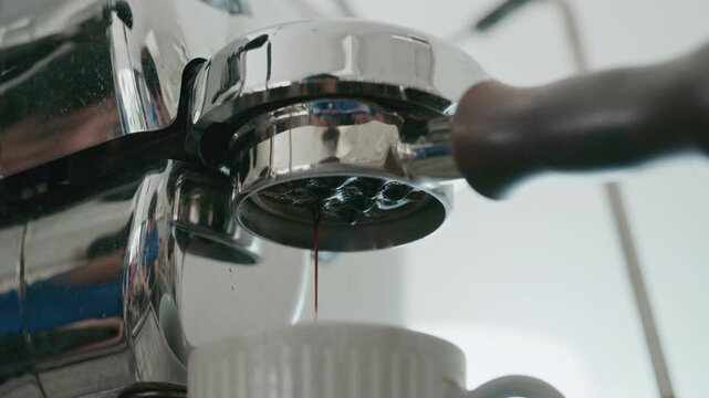 Close up 4K of espresso extraction from a bottomless portafilter into a white cup.