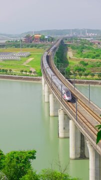 Two modern high-speed trains pass each other in opposite directions on the railway bridge over the river.