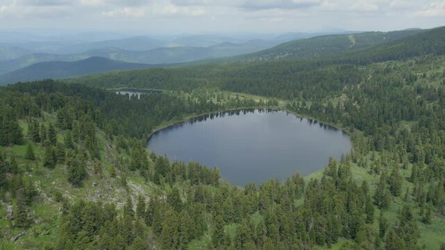 Drone footage of Karakol Lakes, a group of alpine lakes among conifer taiga and rolling ridges in Altai Republic, Russia, under cloudy summer sky