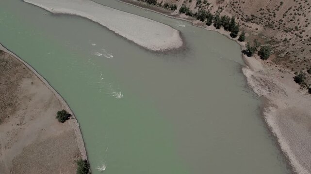 Drone footage of the confluence of the Chuya and Katun rivers with turquoise water, gravel banks and arid hills in Altai Republic, Russia