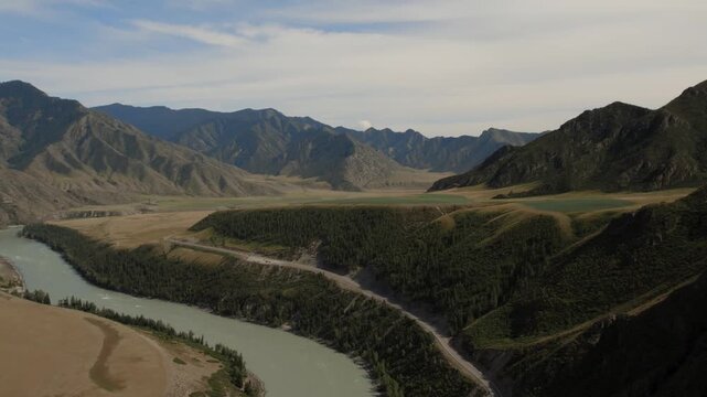 Wide aerial footage of the turquoise Katun River winding through a mountain valley beside the Chuysky Trakt highway in the Altai Republic, Russia, on a clear day