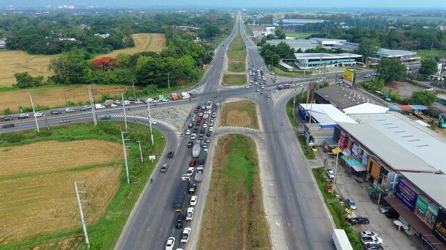 High-angle 4K aerial perspective of a busy regional highway junction, featuring heavy traffic flow and urban infrastructure integrated with rural landscapes.