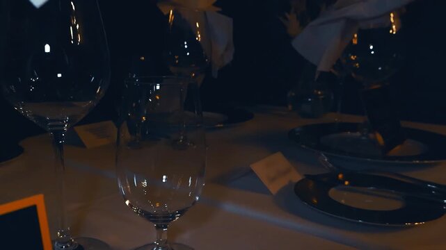 Elegant table setting in a fine dining restaurant at night, with empty wine glasses, plates, and cutlery on a white tablecloth, creating a sophisticated and romantic atmosphere for a formal dinner