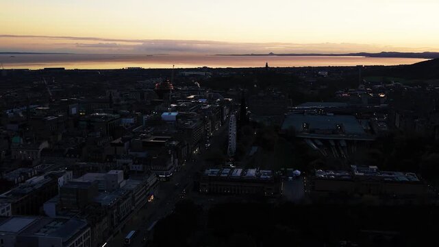 Aerial view of Edinburgh city at sunrise with warm light over the skyline and the Firth of Forth on the horizon