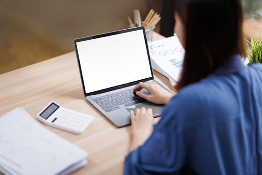 Woman working on laptop with white screen working on a laptop with a blank white screen mockup, ideal for demonstrating websites or applications in a modern home office setting.