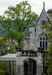 Fototapeta premium A stone castle in a forest with a river and mountains in the background 