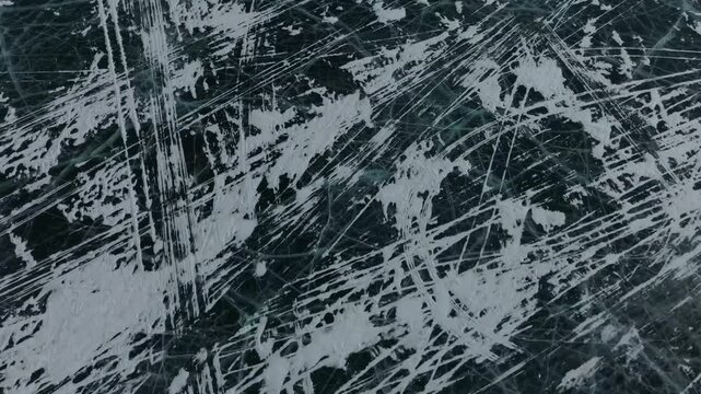 Top down aerial footage of dark transparent ice with natural cracks and snow patches on Maloye More strait, Lake Baikal, Irkutsk Oblast, Russia