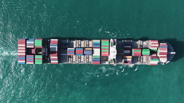 Freight container loaded on cargo vessel. Aerial cargo ship passing harbor. Cargo business. Container ship. Shipping logistics. Commercial shipping import. Cargo ship at sea, aerial top view
