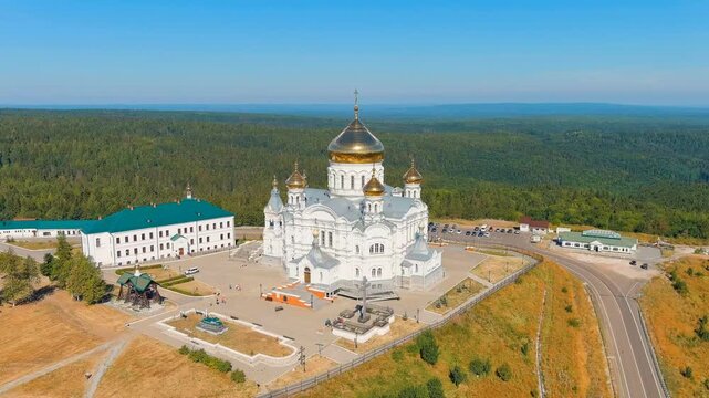 Russia, Perm region. Belogorsk St. Nicholas Missionary Monastery, Drone footage of the Cathedral of the Exaltation of the Holy Cross with gleaming golden domes atop Belaya Gora. Drone footage, Point 