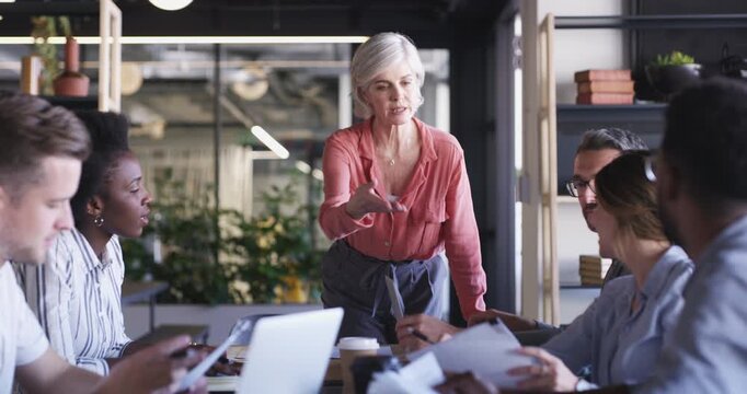 Group meeting, paperwork and mature professional woman, manager or executive journalist consulting on research story development. Documents, creative article process and reporter teamwork with staff