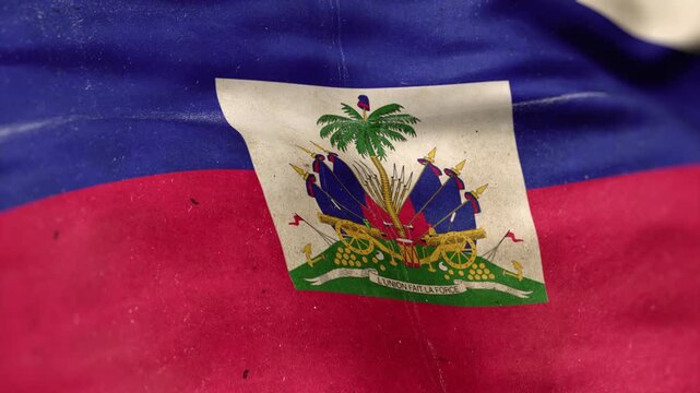 A Haiti flag, made of old cloth, dirty and stained, flutters in the wind. A Worn Haiti Flag Waves In The Breeze.