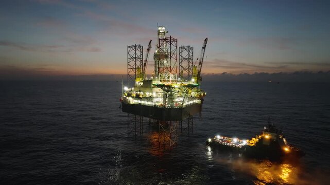 Aerial top view of offshore jack up rig and offshore platform during sunset for oil and gas exploration and production. 