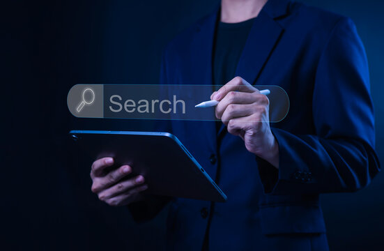 Businessman using digital search interface on virtual screen with tablet and stylus pen. Technology concept for online search, SEO, data analysis, internet marketing and smart business.