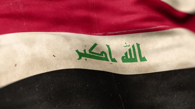 A Iraq flag, made of old cloth, dirty and stained, flutters in the wind. A Worn Iraqi Flag Waves In The Breeze.