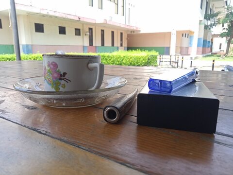 Eye Level Composition Of Black Coffee And Smoking Accessories On Table Side Angle