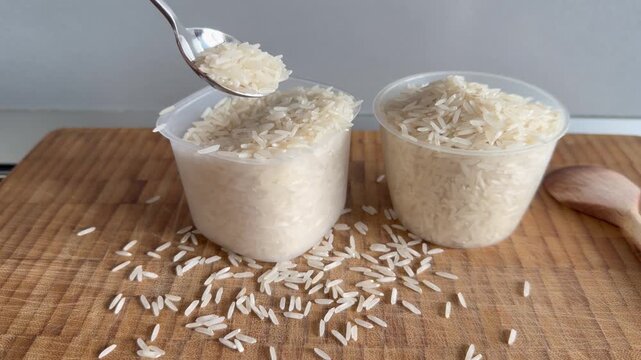 A woman's hand spoons rice into a measuring cup, close-up. Basmati rice.