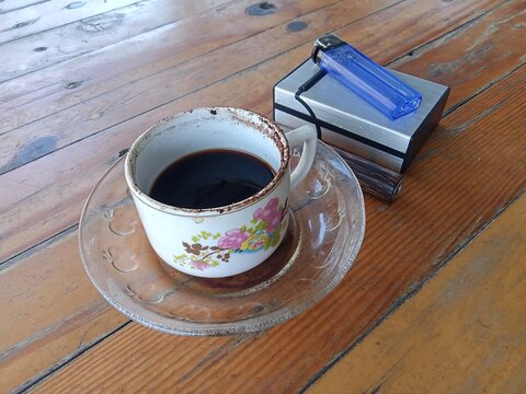 Cup Of Black Coffee With Smoking Accessories On Table