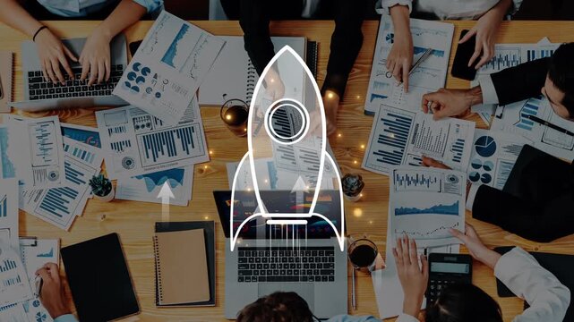 A dynamic team gathers around a table filled with charts and laptops, showcasing collaboration and strategy planning for business growth with a rocket icon symbolizing innovation. Raster