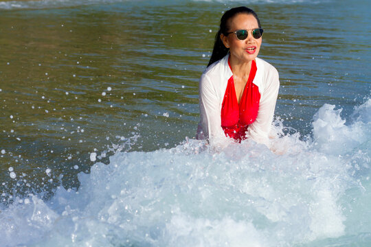 Woman in red swimsuit enjoy with wave on beach