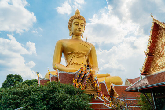 Giant golden Buddha statue rising above traditional temple roof at Wat Paknam in Bangkok