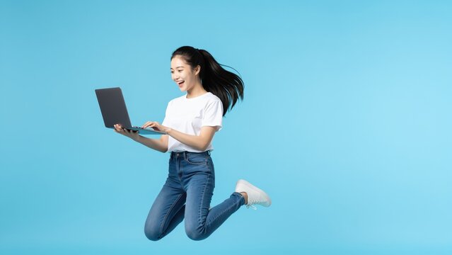 Jumping for Joy with Laptop: A dynamic shot capturing a person mid-air, laptop in hand, radiating elation against a bright background, showcasing the excitement of modern technology.