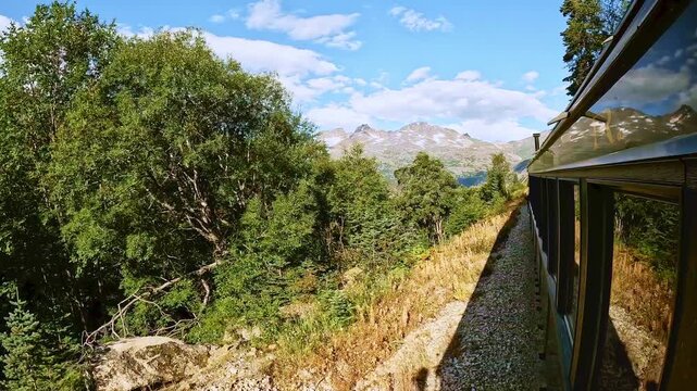 White Pass train ride between Skagway Alaska and Whitehorse Yukon Canada. Beautiful sunny day with white clouds and blue sky