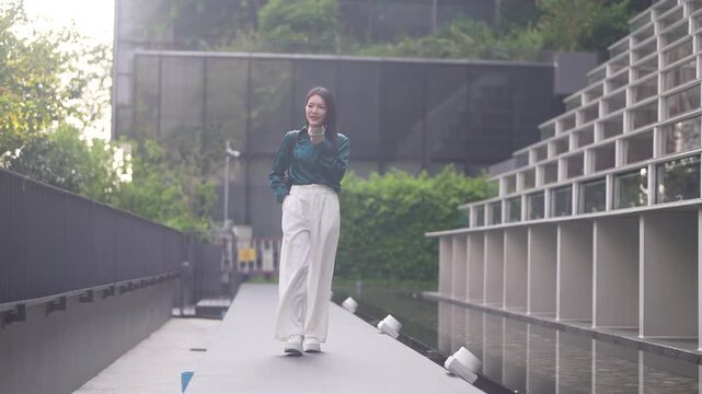 Smiling asian business woman using AI voice assistant on smartphone outdoors, Smart agent technology, Female corporate employee recording audio message or speaking to artificial intelligence app