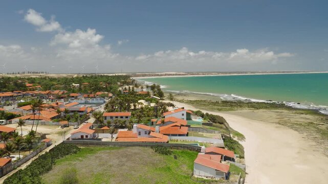Taiba village in Sao Goncalo do Amarante municipality Ceara state Brazil South America with beachfront houses and palm trees along sandy shoreline and turquoise water drone ascent with lateral pan