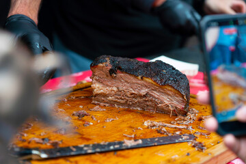 Fototapeta premium Gloved hands cutting meat on a wooden board in a cinematic food preparation scene. 