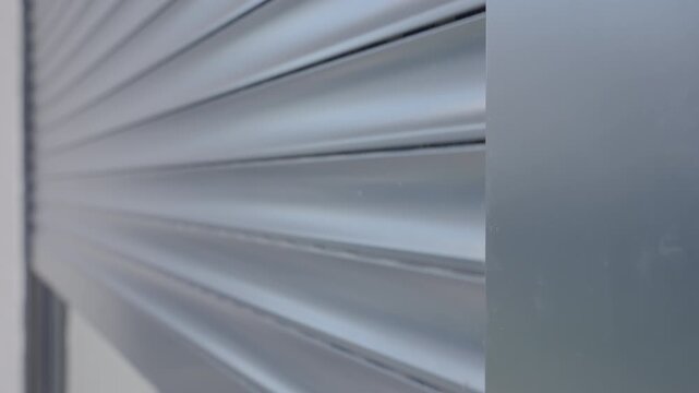 Automatic exterior roller shutter closing modern exterior window. Close up view of electric blind panel moving over glass surface. Concept of home security, privacy, sun protection