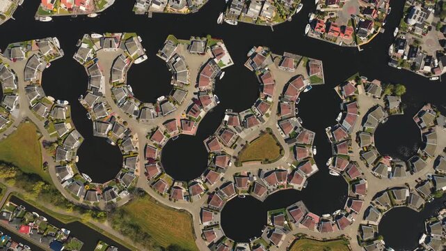 Aerial view of unique circular residential housing developments surrounded by water basins and green lawns in Lemmer, Friesland, Netherlands.