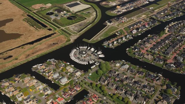 Aerial view of modern waterfront houses and a circular boat marina along the canals of Lemmer, Friesland, Netherlands.