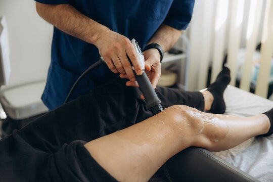 Physiotherapist performing shockwave therapy on patient's knee